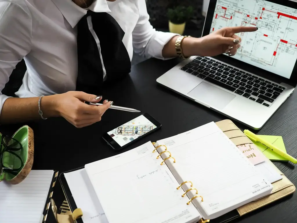 Person pointing at a laptop showing a building plan